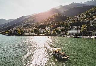 Bootsfahrt auf dem Lago Maggiore bei Brissago im warmen Abendlicht mit Blick auf Berge, See und Ufer.